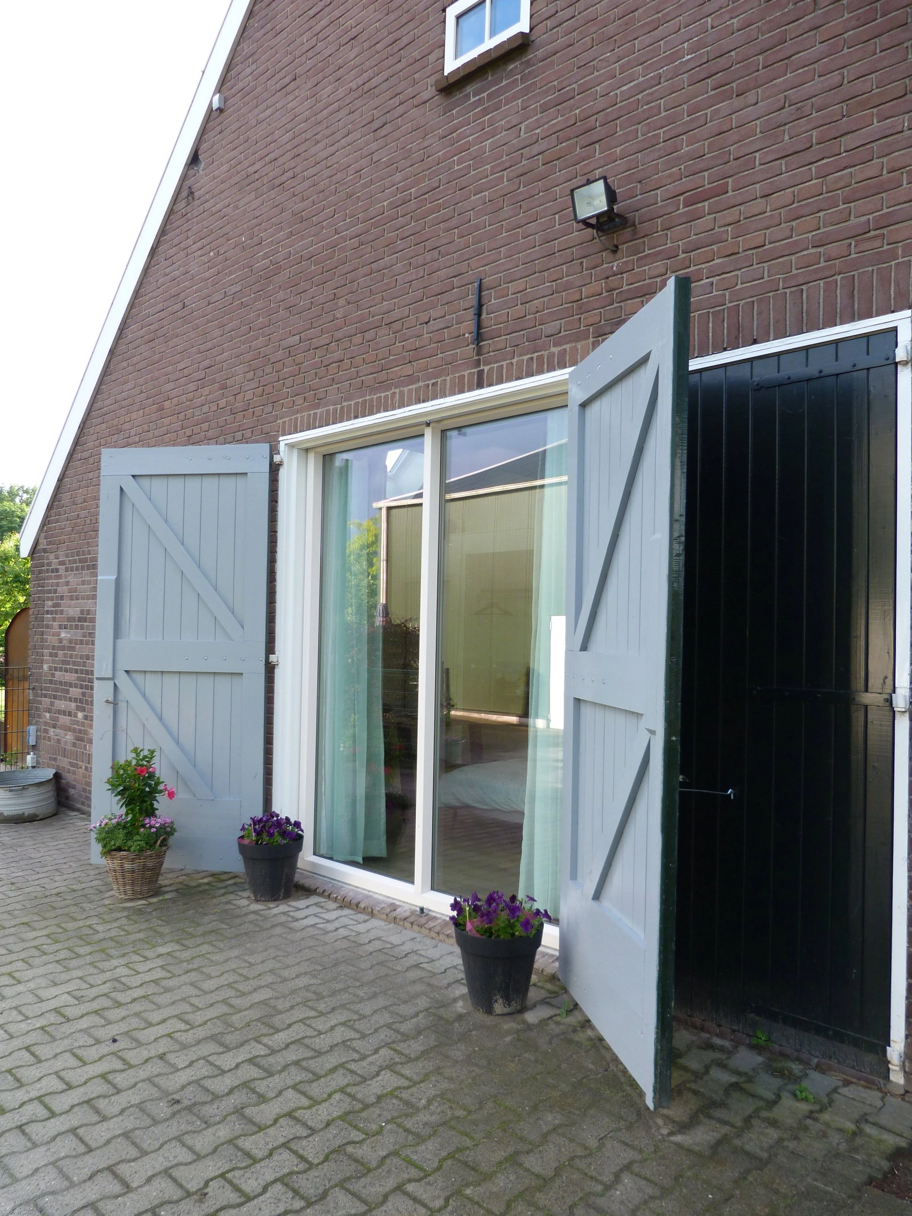 Ingang met grijsblauwe luiken en een terras