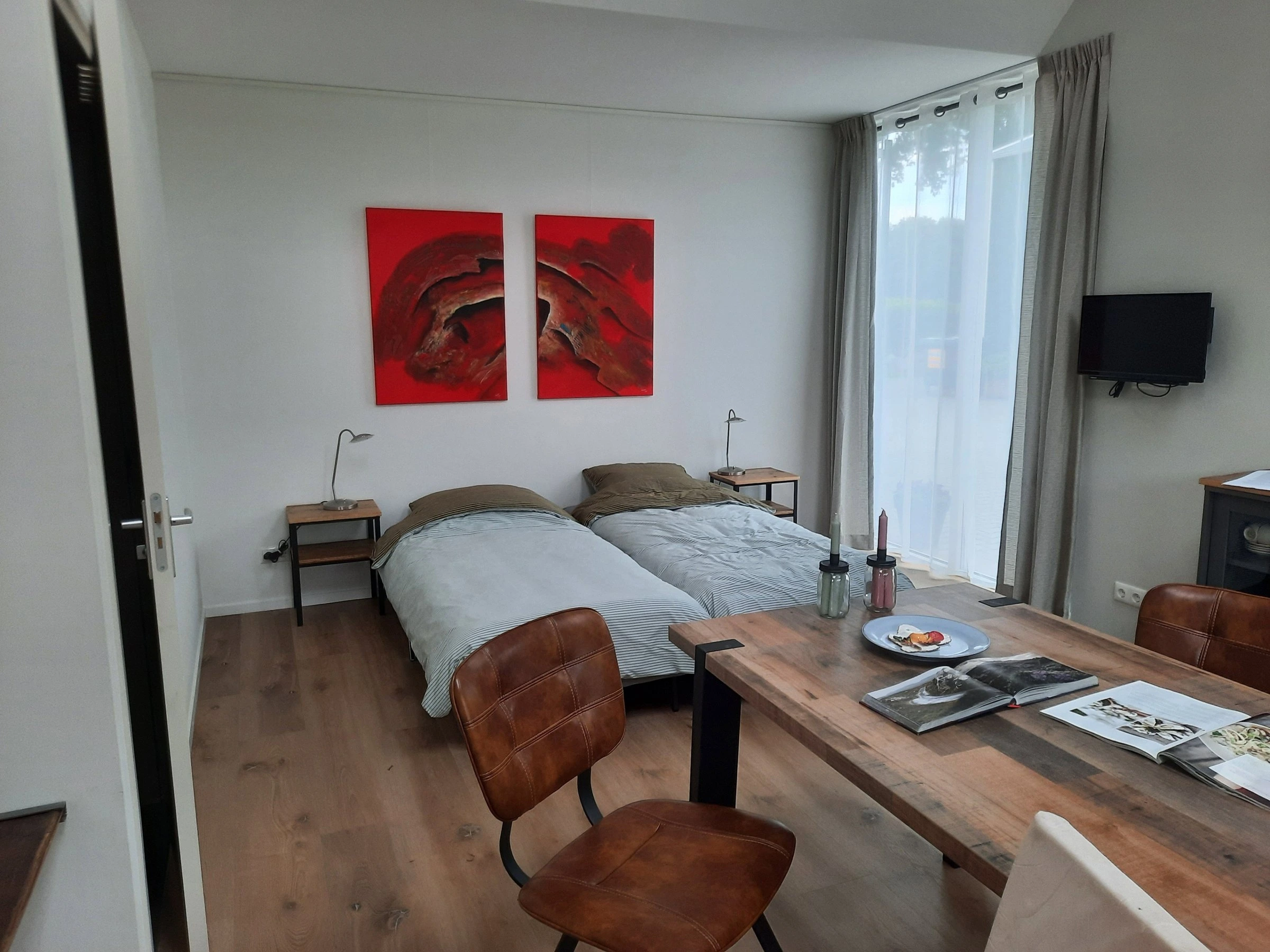Woon- en slaapruimte met twee bedden en een eettafel